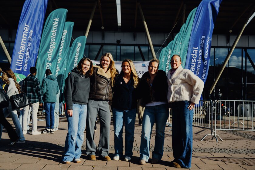 Fem blide jenter som står utenfor inngangen til Håkons hall, med mange beachflagg for utdanningsmessa i bakgrunnen. Foto: Eivind Fuglehaug - Klikk for stort bilde